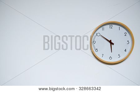 Portrait Of Yellow Circular Wall Clock On The White Wall Background. The Clock Has Time Of Round Abo