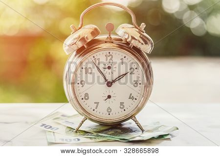 Old And Rusty Alarm Clock And 100 Hundredth Euro Banknotes. Business Or Time And Money Concept