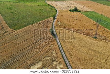 Aerial Drone Perspective On Damaged Wheat Field After Wind Storm, Rural Landscape With Asphalt Road.