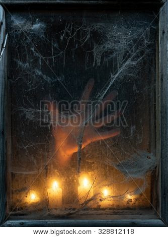 Scary Halloween Party Background. Hand of a ghost in the dark. Old spider web in the light of candles