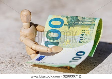 Wooden Dummy Puppet Holding Hundredth Euro Banknote. Money Or Business Concept. Abstract Conceptual 
