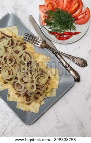 Beshbarmak Is A National Kazakh Dish - Square Pasta With Boiled Meat And Onions. On A Light Backgrou