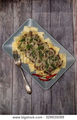Beshbarmak Is A National Kazakh Dish - Square Pasta With Boiled Meat And Onions. On Wooden Backgroun