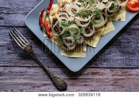 Beshbarmak Is A National Tatar Dish - Square Pasta With Boiled Meat And Onions. On A Black Backgroun