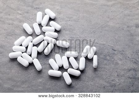 Closeup Scattered White Medicine Vitamins, Pills, Drugs On Gray Background. White Food Diet Suppleme