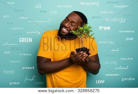 Happy Boy Hugs A Small Tree Ready To Be Planted Over A Light Blue Color. Concept Of Forestation, Eco