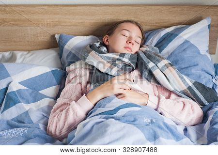 Student Is Lying At Home In Bed With Flu Symptoms. A Girl In Kravata With High Temperature