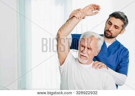 Senior Patient While Exercise Treatment With His Physiotherapist. Rehab At Medical Center