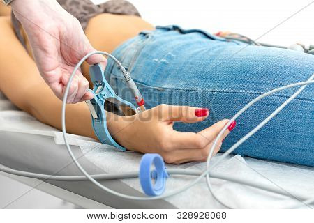 The Doctor Attaches The Electrodes Of The Ecg Pegs To The Patients Wrist.