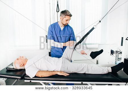 Kinesiologist Doing Therapeutic Exercises For An Elderly Patient. Kinesitherapy At The Medical Cente
