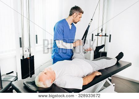 Kinesiologist Doing Therapeutic Exercises For An Elderly Patient. Kinesitherapy At The Medical Cente