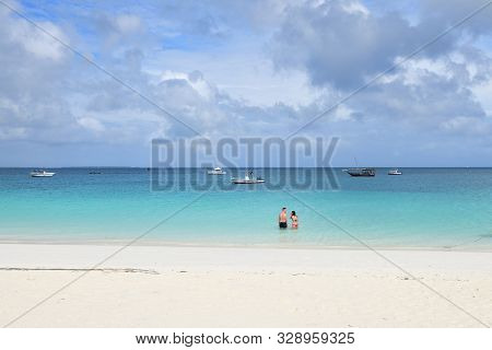Kendwa, Tanzania - October 3, 2019: Blue Transparent Water And Couple Tourist In Ocean, Kendwa Beach