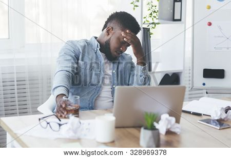 Business Problems. Depressed Black Businessman Drinking Alcohol At Workplace In Office, Having Finan