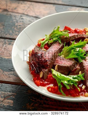Beef Steak With Romesco Sauce, Nuts And Vegetables On White Plate