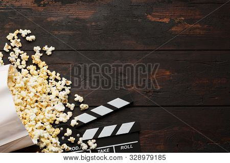 Cinema Concept. Popcorn In A Box And Movie Clapper On Wooden Background Top View. Free Space.