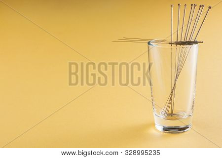 Silver Needles For Traditional Chinese Medicine Acupuncture. Yellow Background. Close-up. There Is S