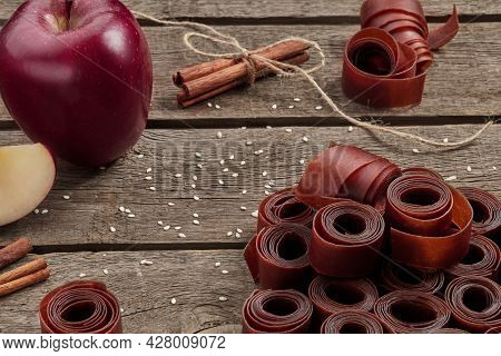 Rolls Of Fruit Leather On Wooden Surface With Apple And Cinnamon