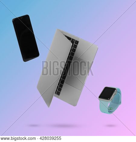 Laptop  Computer, Smart Phone And Smart Watch While Levitating In The Air On A Background Illuminate