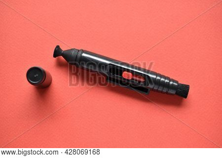 Brush For Cleaning Optics On A Red Background