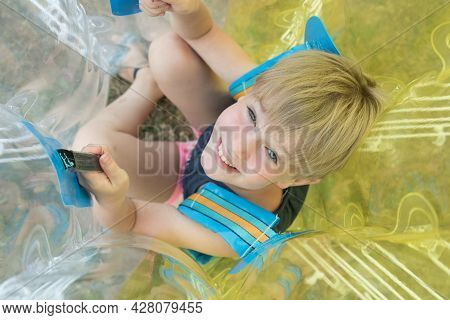 A Child In A Bumperball. Portrait Of A Happy Laughing Child. Happiness, Fun And Laughter