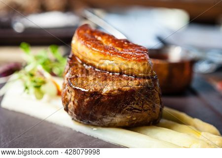Tournedos Rossini. Foie gras, Black Angus beef tenderloin, white asparagus, red wine sauce. Delicious healthy traditional food closeup served for lunch in modern gourmet cuisine restaurant.