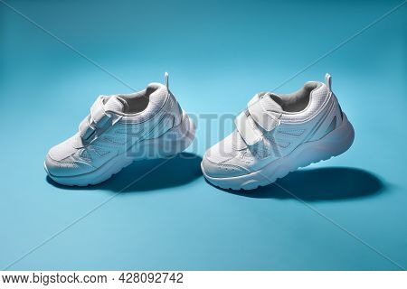 Two White Child Flying In The Air Sneakers Simulate Walking Isolated On A Blue Background