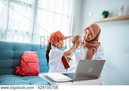 Daughter With School Uniform Highfive With Mother During Online Class At Home