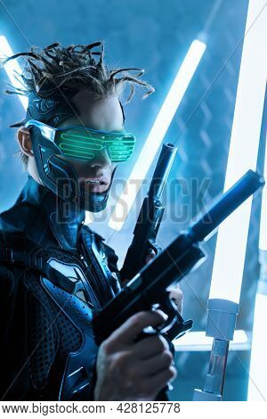 Militant cyberpunk warrior in a protective suit fights with guns in his hands in neon light. World of the future. Game, virtual reality.