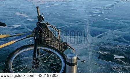 Man And His Bicycle On Ice. He Looks At The Beautiful Ice In The