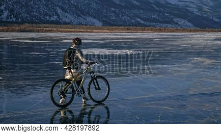 Woman Stands Near Her Bike On Ice. The Girl Cyclist Stopped To R