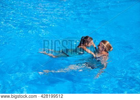 Grandmother And Granddaughter In The Pool. Grandmother And Granddaughter Play Catch-up In The Clear 