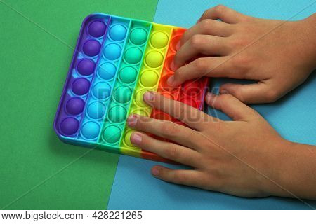 Popular Silicone Colorful Antistress Pop It Toy For Child On Green And Blue Background. Kid Hands Pl