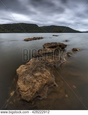 A Close Up Of A Rock Next To A Body Of Water