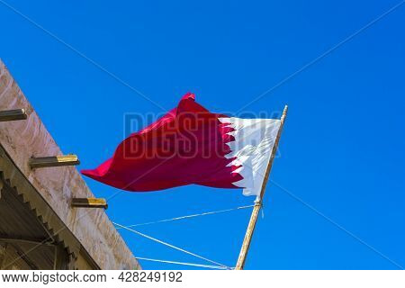 National Flag Of Qatar On A Flagpole In Front Of Blue Sky