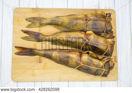 Terpug (latin: Hexagrammos Stelleri) Hot Smoked Without Heads Tied With A Rope On A Wooden Board. Fo