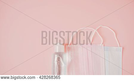 Two Medical Face Masks, Pink And Blue, And Bottle Of Blue Alcohol Gel On Sweet Pink Background, Camp