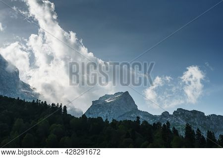 Rocks And A Pass With A Blue Sky With Sun Rays Breaking Through The Clouds. Fisht Oshten Is A Mounta