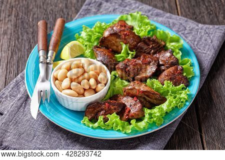 Chicken Liver Fry, Kaleji Fry, Served On Lettuce Leaves With Butter Beans And Lemon Wedges On A Blue