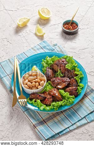 Chicken Liver Fry, Kaleji Fry, Served On Lettuce Leaves With Butter Beans And Lemon Wedges On A Blue