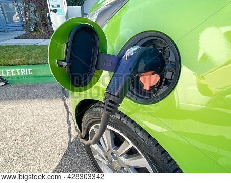 A Lime Green Electric Vehicle Charging At A Free Public Charging Station.
