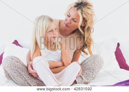 Mãe e filha falando sentado numa cama