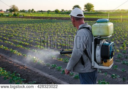 A Farmer With A Mist Fogger Sprayer Sprays Fungicide And Pesticide On Potato Bushes. Protection Of C