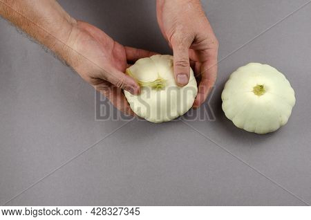 Man Holds White Raw Fruit Pattypan Squash On An Against Grey. Hands Of A Grown Man With A Ripe Fruit