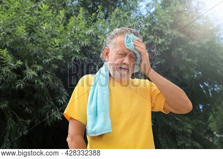 Senior Man With Towel Suffering From Heat Stroke Outdoors