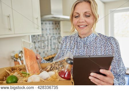 Woman Unpacking Online Meal Food Recipe Kit Delivered To Home
