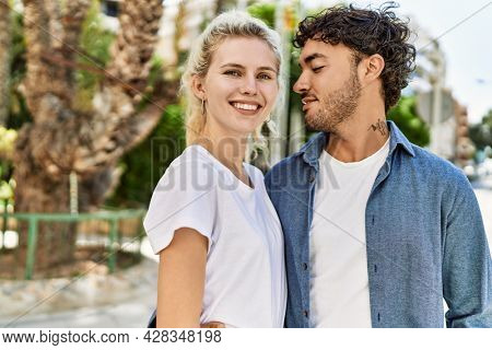 Young beautiful couple of caucasian girlfriend and hispanic boyfriend hugging in love outdoors on a sunny day. Woman and man smiling happy dating relationship