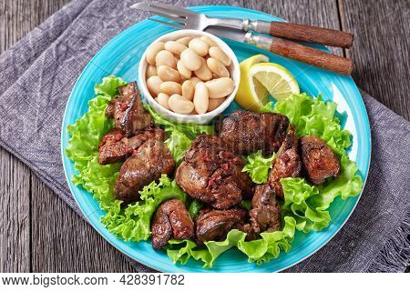 Chicken Liver Fry, Kaleji Fry, Served On Lettuce Leaves With Butter Beans And Lemon Wedges On A Blue