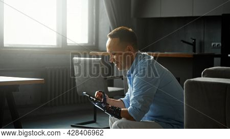 Concentrated disabled guy cyborg types and switches on smartphone at home