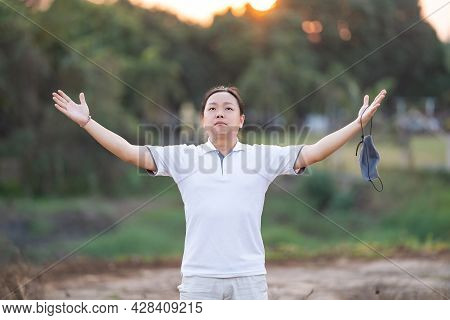 Asian Man Take Off Mask And Rise His Hand Up In Golden Twilight Time.