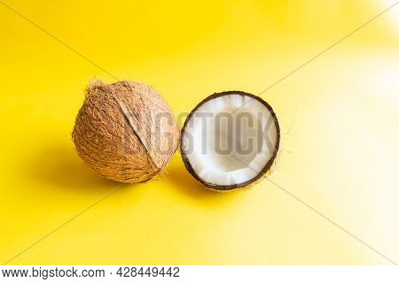 Coconut Of Which Husk Removed And One Half Side Of The Coconut With Shell On The Yellow Colored Back